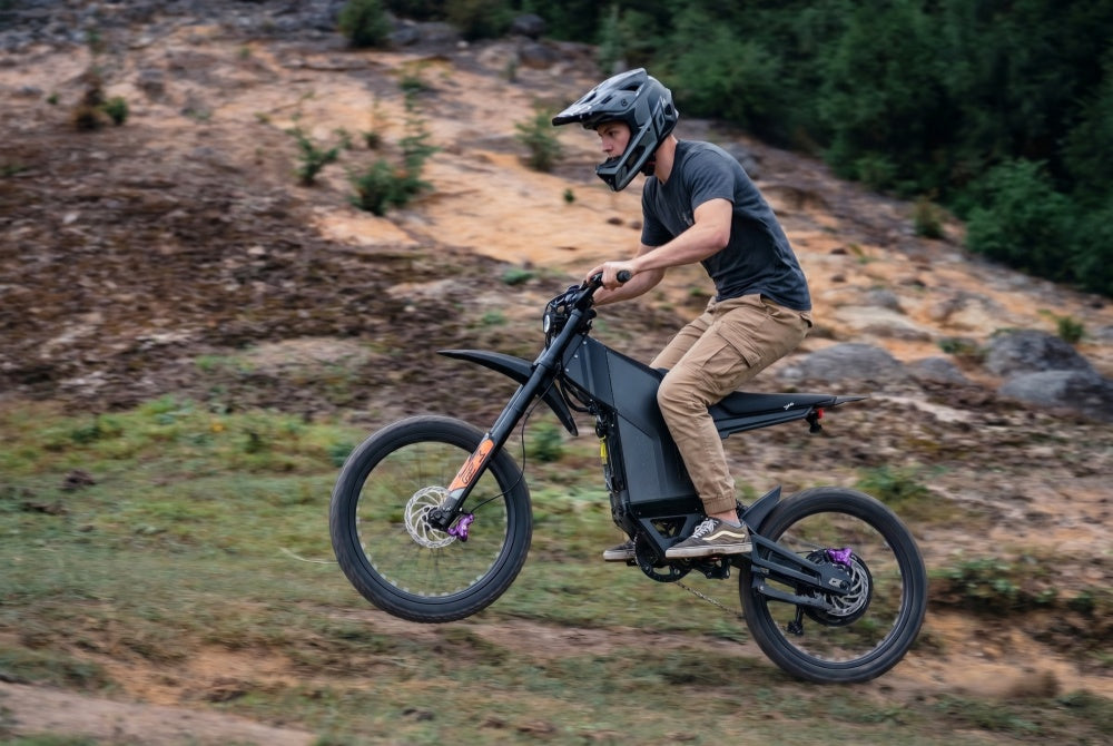A rider accelerating up a steep dirt trail on the EKX GTS X22 fast electric dirt bike, demonstrating the instant torque of its 10,000W peak motor.