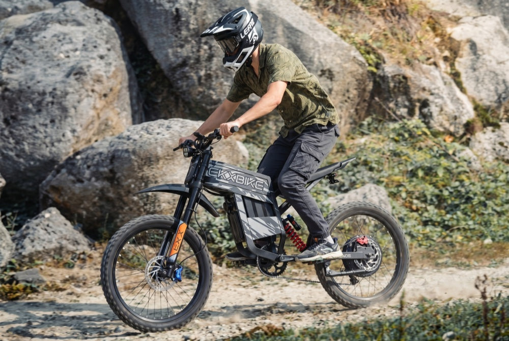 A rider navigating a rocky off-road trail on the EKX TX1 electric dirt bike, powered by a 6000W high power motor