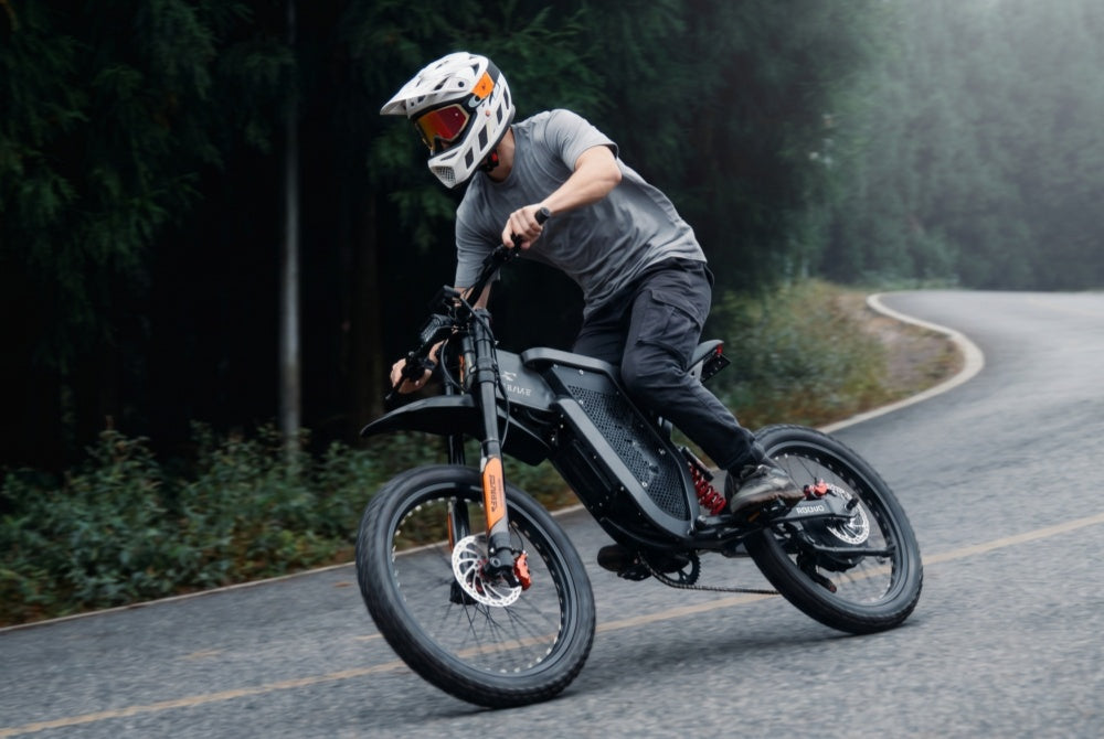 A young trendy rider cornering on a winding forest road with the EKX X21 Max electric dirt bike, demonstrating its 55-mile pure-electric range and 60V 30Ah removable battery endurance.